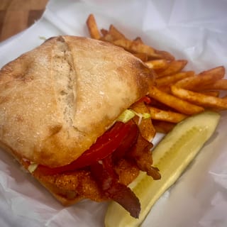 Asiago Chicken Sandwich Golden, crispy chicken topped with smoky bacon, creamy ranch dressing, and rich Asiago cheese, served on toasted ciabatta bread with a side of golden fries.