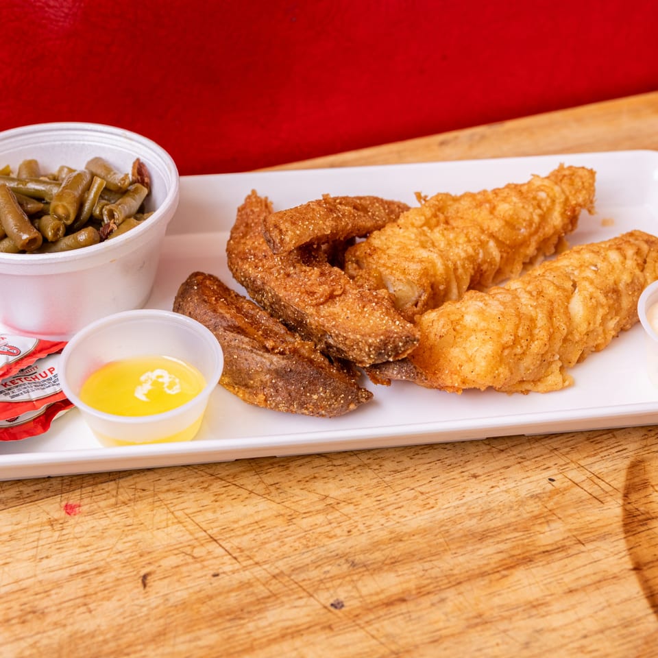 Our Place's fried fish and potato wedges with a side of green beans and melted butter.